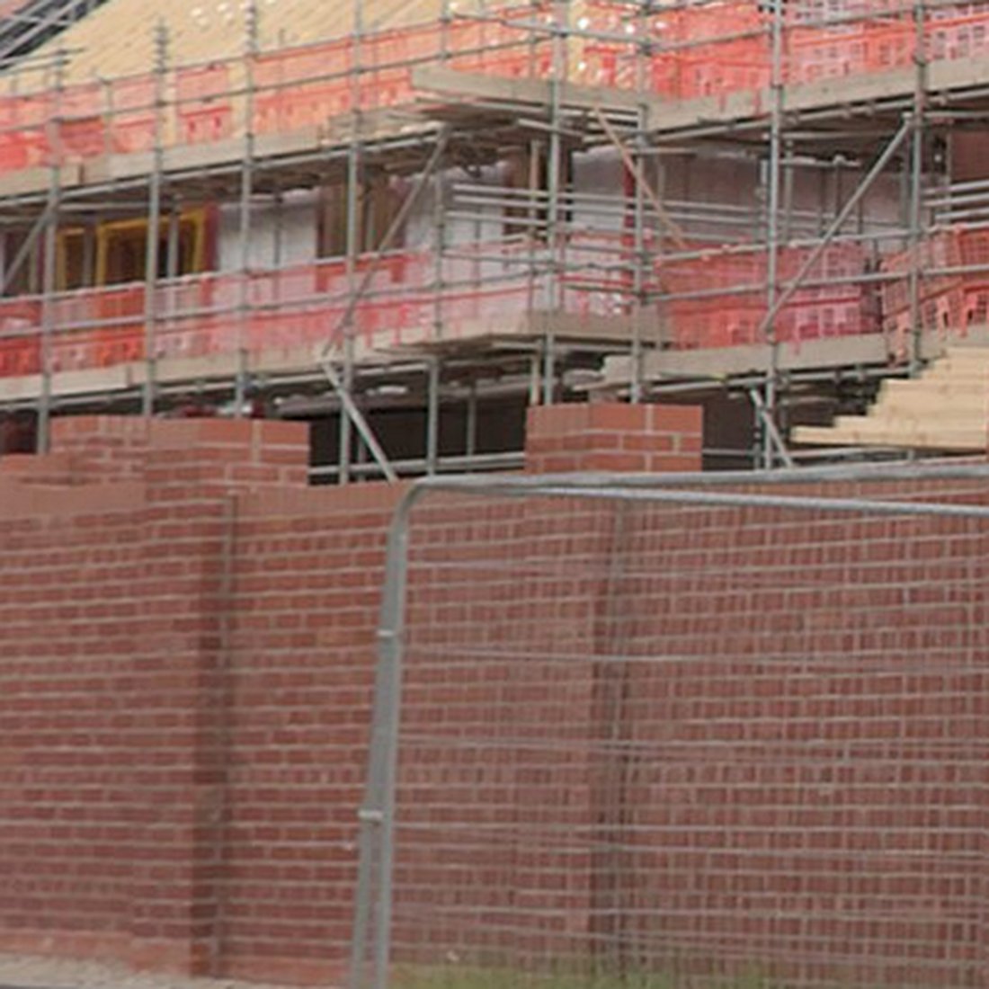 A new red brick wall with piers, courses laid