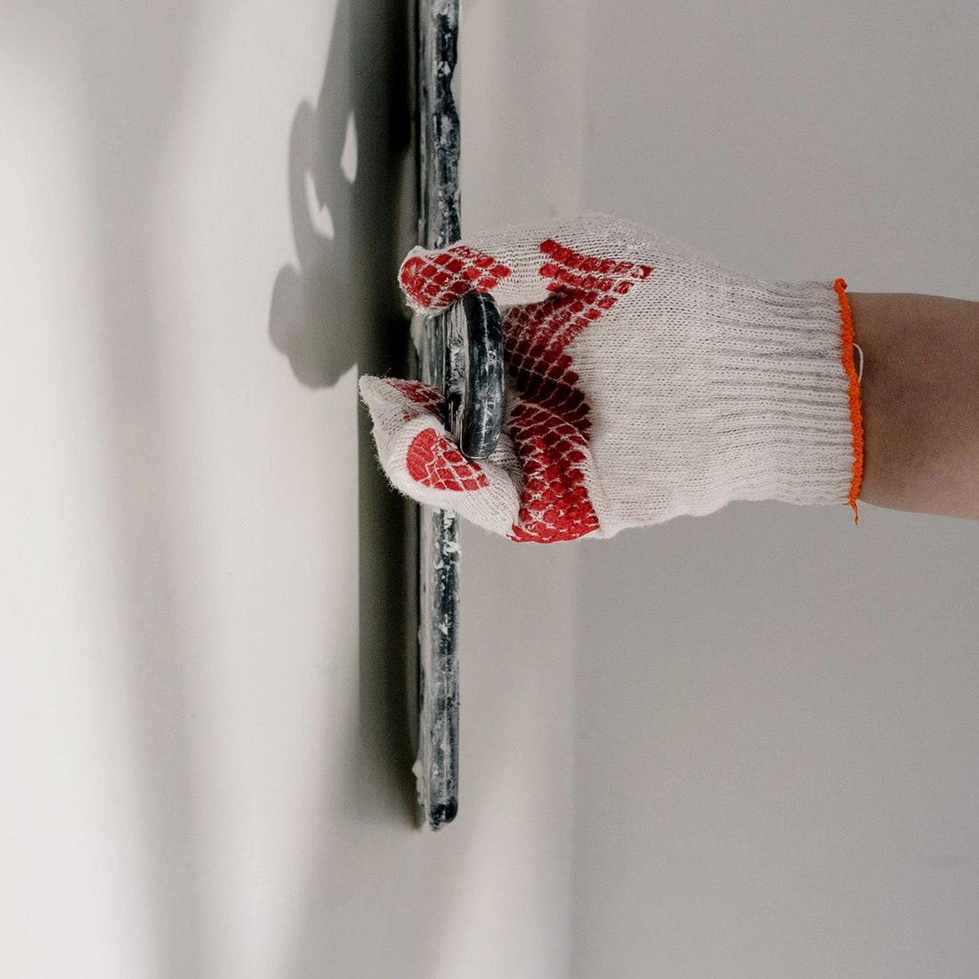 A finishing trowel smoothing a white wall