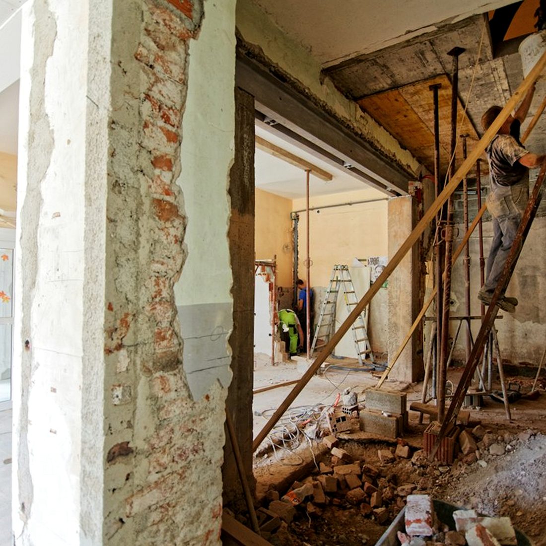 Plaster cut back to exposed brick, with rubble and scaffold inside
